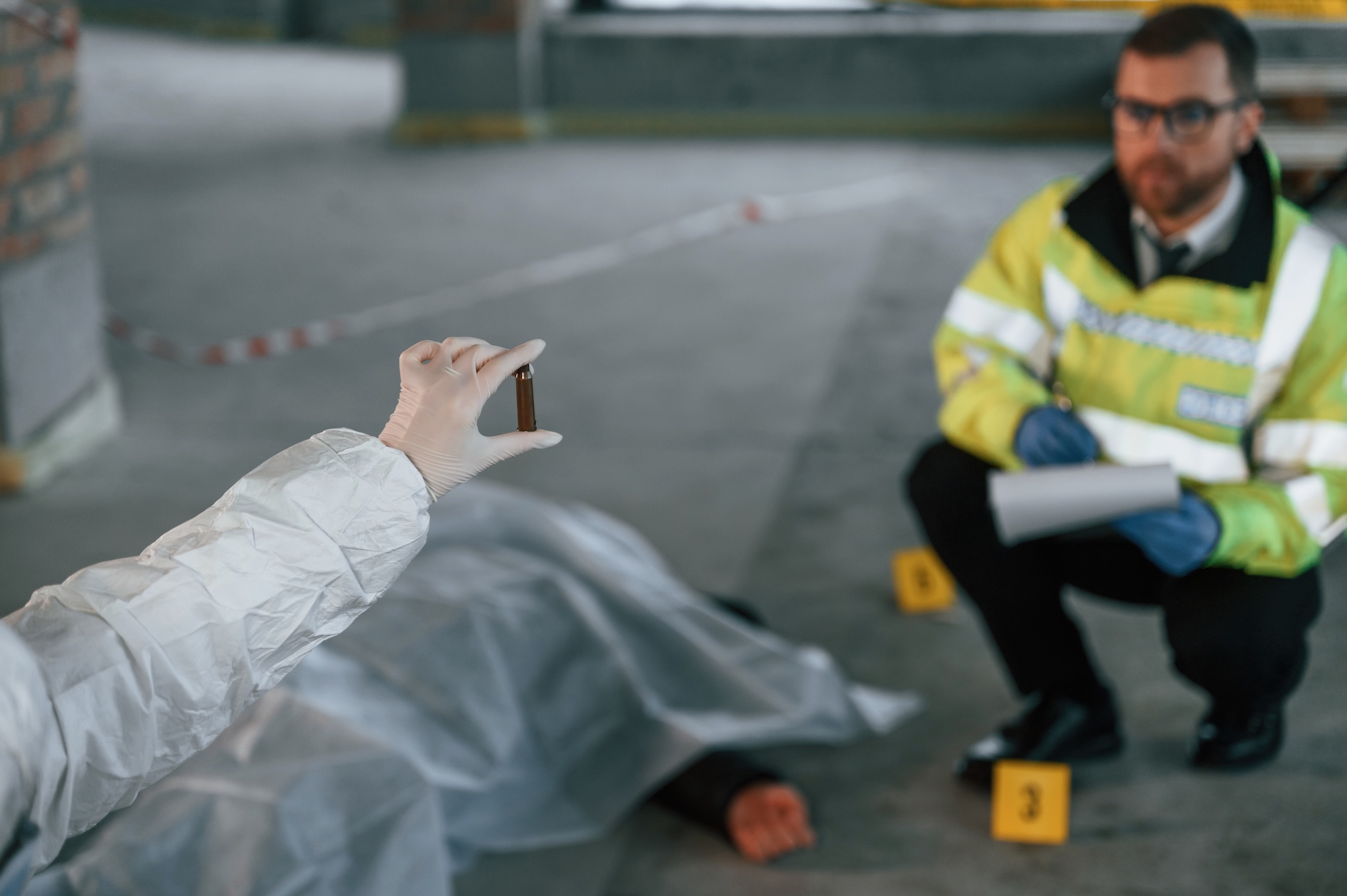A woman is holding a shell casing. Detectives are collecting evidence in a crime scene near dead body.